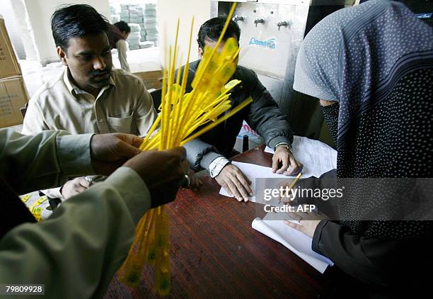 Pakistani fenmale election official signs to receive election material at a distribution station in Lahore on February 17 a day before the country's...