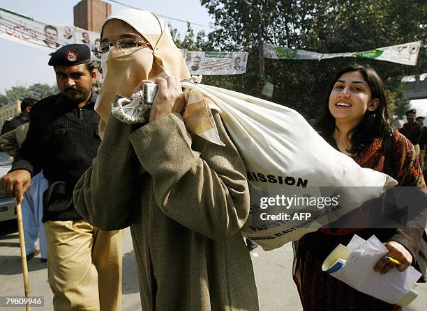 Young Pakistani female election official carries a bag of election material outside a distribution station in Lahore on February 17 a day before the...