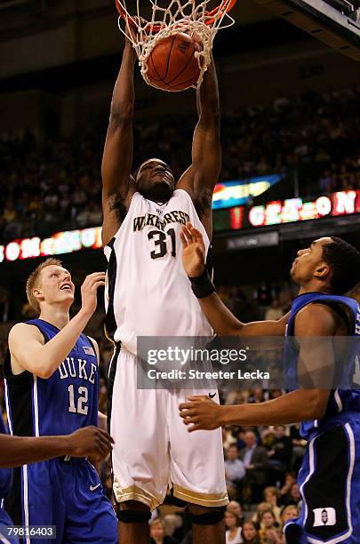 Teammates Gerald Henderson and Kyle Singler of the Duke Blue Devils watch as Jamie Skeen of the Wake Forest Demon Deacons dunks the ball during their...