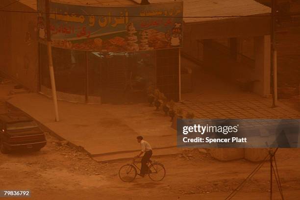 Man rides his bike during a sandstorm that has enveloped a residential neighborhood February 19, 2008 in Baghdad, Iraq. Seasonal sandstorms have...