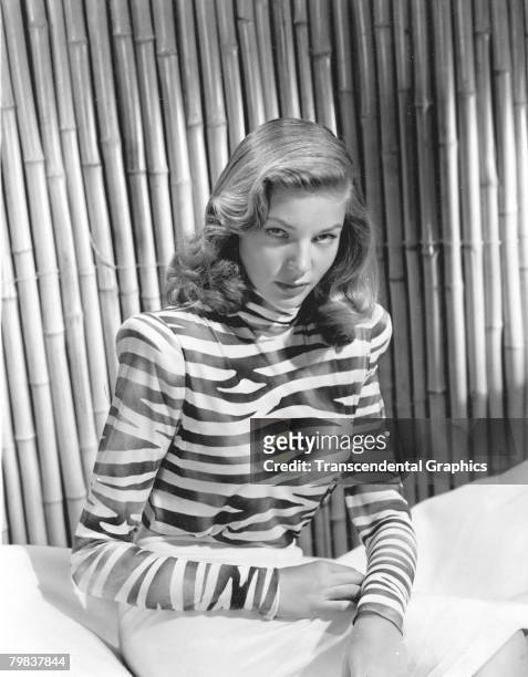 Portrait of American actress Lauren Bacall , 1940s. She wears a zebra-stripe print blouse and poses in front of a bamboo curtain.