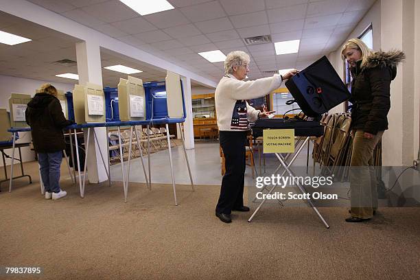 Julie Olk casts a paper ballot while Election Inspector Ruth Foley assists Laurie Pagel with an electronic ballot at the village polling place in the...