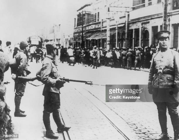 Japanese troops search members of the Chinese population of the British concession in the North China Treaty Port of Tientsin, during the Second...