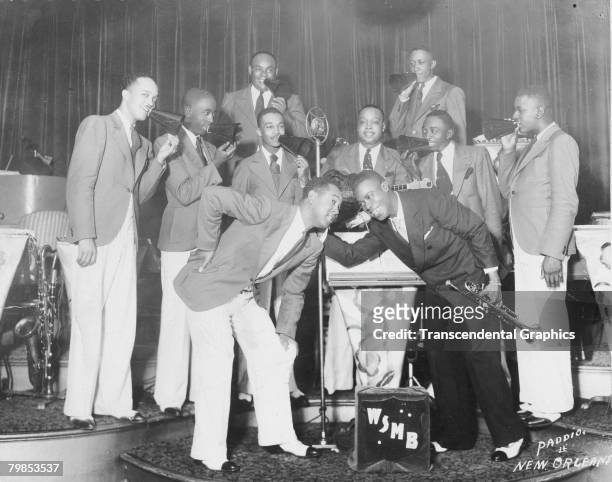 American jazz musician Louis Armstrong smiles as he poses on stage with a band for the WMSB radio station in New Orleans, Louisiana, 1920s.