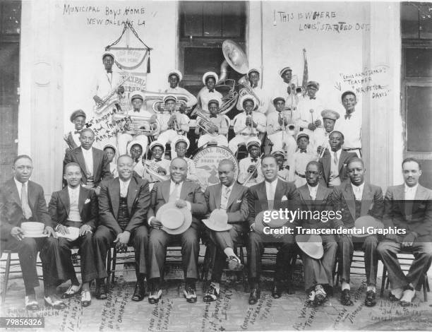 Portrait of American jazz musician Louis Armstrong and his band pose with members of the Municipal Boys' Home Brass Band and their teacher Peter...