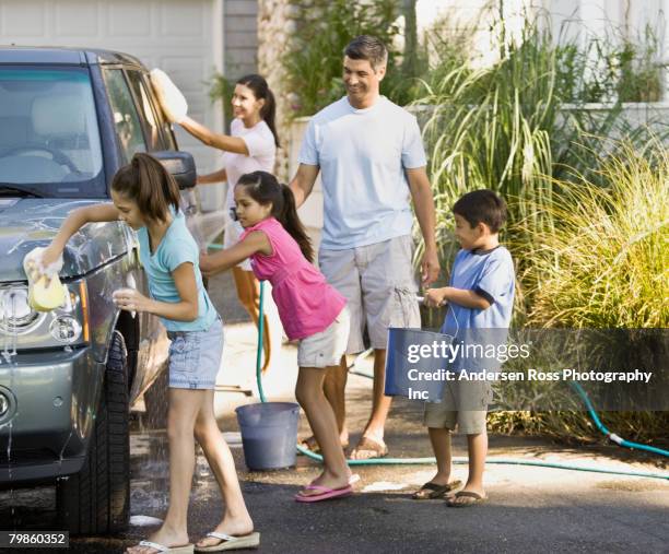 hispanic family washing car - daily bucket stock-fotos und bilder