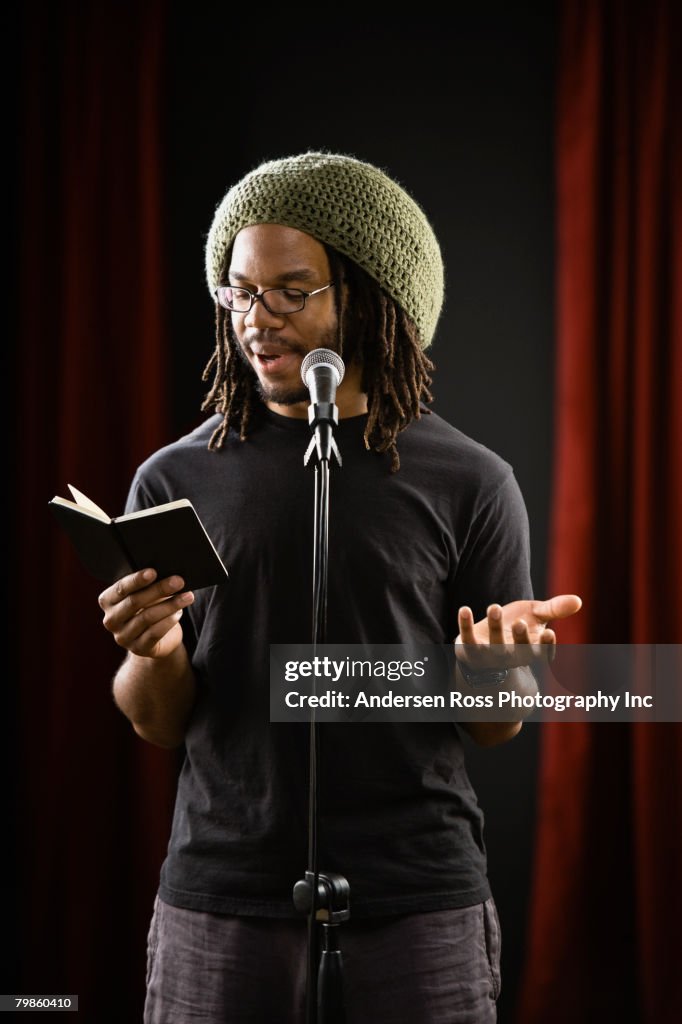 African man reading into microphone