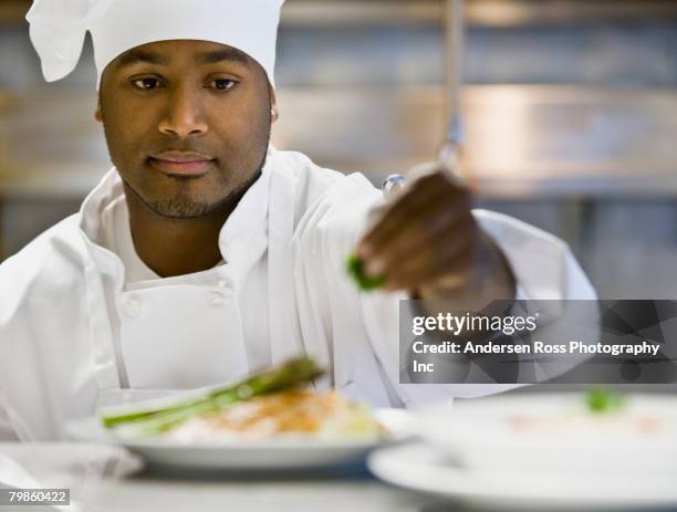 african male chef garnishing plate of food - シェフの制服 ストックフォトと画像