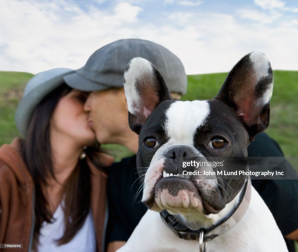 Multi-ethnic couple kissing behind dog