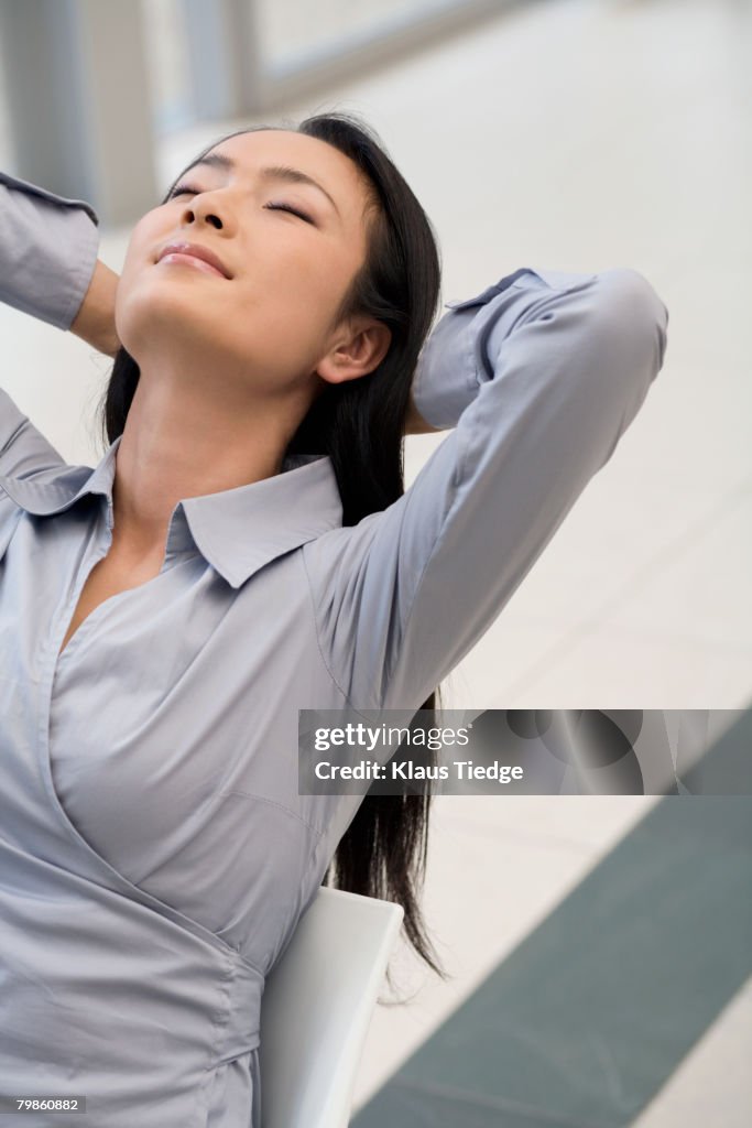 Asian businessman with hands behind head