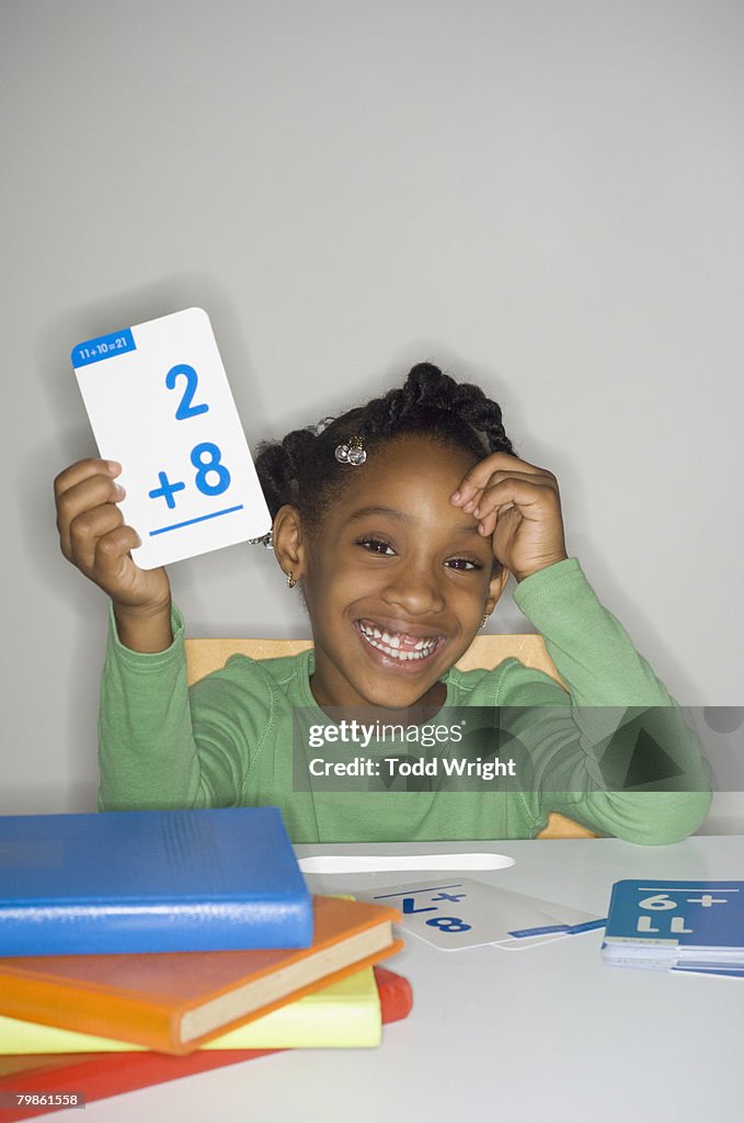 African girl holding addition flash cards