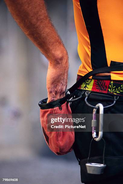 climber dipping into bag of chalk - chalk bag stock-fotos und bilder