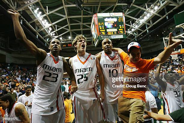 James Dew, Jonathan Stratton and Landon Glover of the Miami Hurricanes and a fan celebrate victory over the Duke Blue Devils at BankUnited Center on...