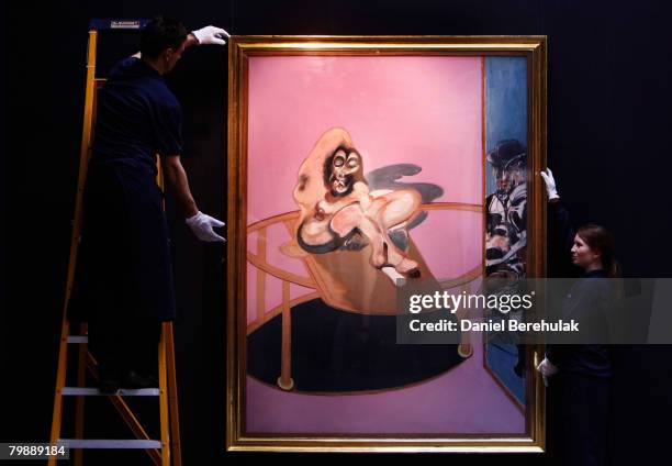 In this photo illustration, Sotheby's employee's appear to hold a painting by Francis Bacon called Study of Nude with figure in a mirror, during a...