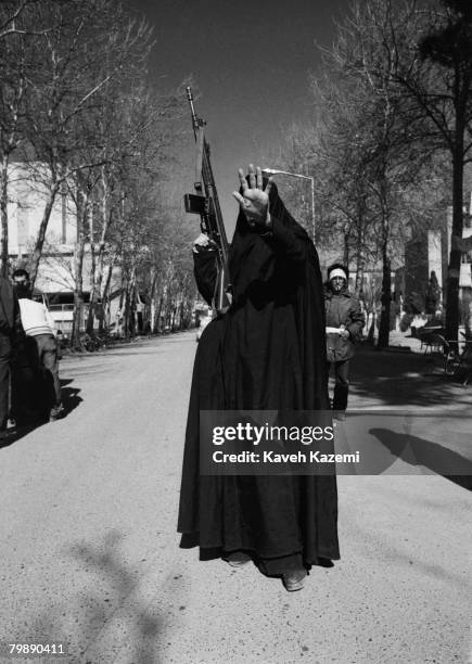 Woman, in black chador and carrying a G-3 machine gun, holds up her hand in a gesture of defiance to the camera, Tehran, 12th February 1979. She is...