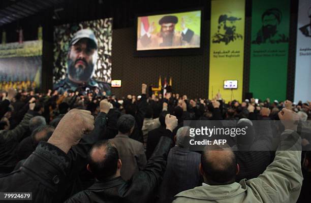 Shiite Muslim men salute as they watch a large screen showing Hassan Nasrallah, the leader of the Shiite Muslim Lebanese militant group, as he...
