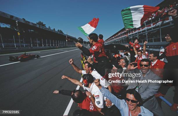 Scuderia Ferrari team members salute Michael Schumacher from the pit lane wall as he takes the chequered flag driving the Scuderia Ferrari Ferrari...
