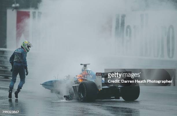 Giancarlo Fisichella of Italy, driver of the Mild Seven Benetton Playlife Benetton B198 Playlife GC37-01 V10 surveys the damage and flames coming...