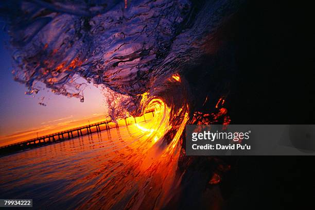 sun shining through breaking ocean wave - david puu stock-fotos und bilder