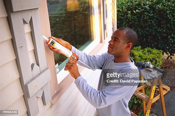 man using chemical on window - caulking stockfoto's en -beelden