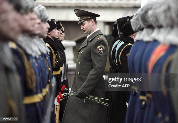 Russian honour guard officer holds flowers as he attends a wreath-laying ceremony at the Unkown Soldier's tomb during a national holiday, the Day of...