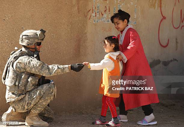 Soldier from the 2nd Battallion 12th Field Artillery Regiment, 4-2 SBCT, distributes sweets to Iraqi girls during a patrol in the town of Baquba, 20...