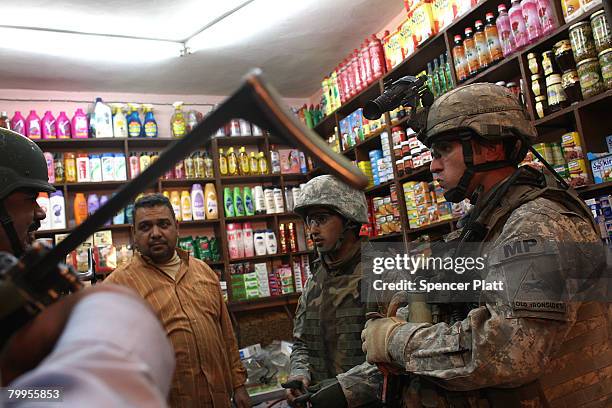 Charles Black, J.R. With the 501st M.P. Company 1st Armored Division speaks to a shop owner while on a joint evening patrol with members of the Iraqi...