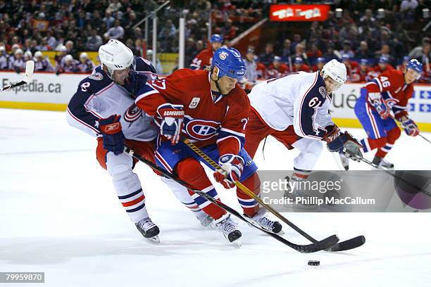 Alex Kovalev of the Montreal Canadiens tries to fight off the checking of Jan Hejda of the Columbus Blue Jackets while carrying the puck into the...