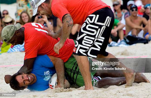 Former NRL player Andrew Johns is tackled by Wendell Sailor in a charity touch football game at Rainbow Bay during the Quiksilver Pro Gold Coast at...