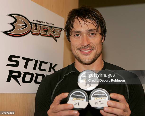 Teemu Selanne of the Anaheim Ducks celebrates scoring a hat trick by posing with his three pucks after the game against the Chicago Blackhawks at...