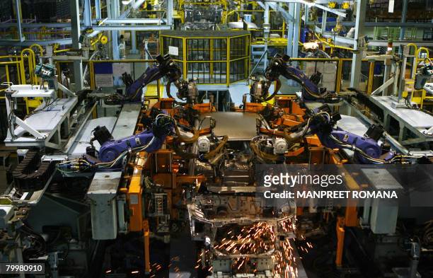 Sparks fly from a robot as it performs spot welding on a car on the production line at Honda Siel Cars India Ltd. Factory in Noida, a satelite town...