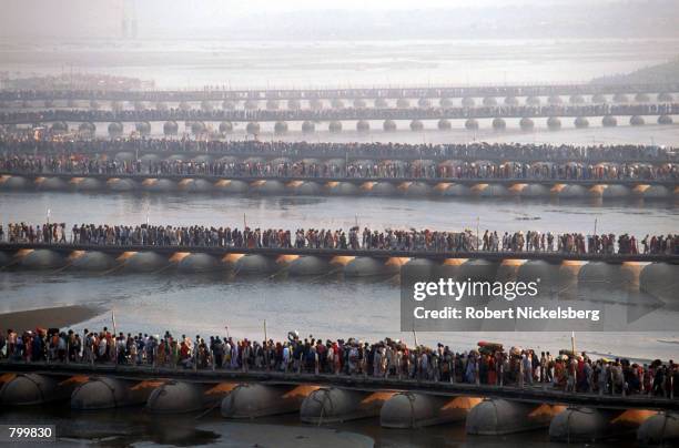 Tens of thousands of Hindu pilgrims walk across pontoon bridges over the Ganges River during the Maha Kumbh Mela festival January 23, 2001 in...