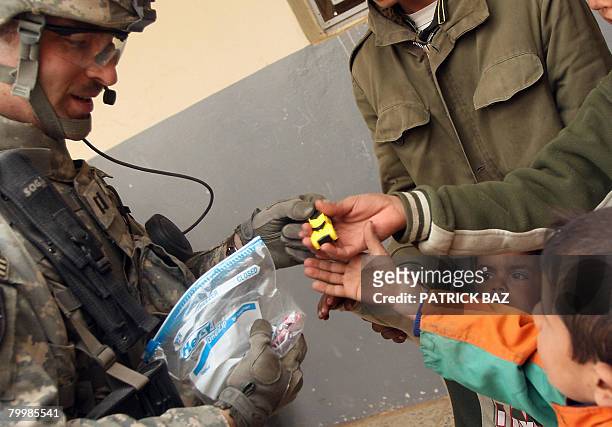 Army Captain Kevin L. James, commander of the 2nd Battalion, 12th Field Artillery Regiment, 4-2 SBCT, distributes toys to Iraqi children on February...