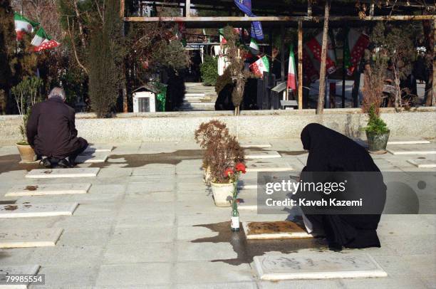 Woman reads from the Holy Qur'an at her son's grave after having cleansed it with rosewater in Behesht-e Zahra cemetery, Tehran, where thousands of...