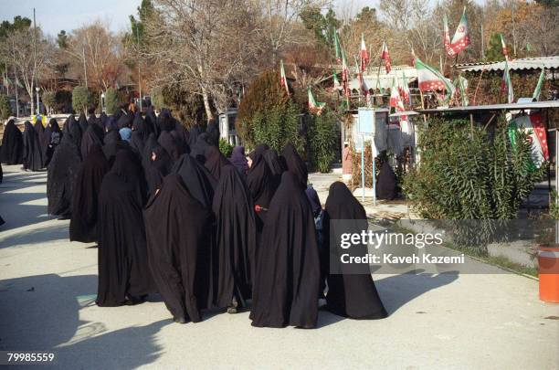 Women in black chador walking to the graves of their loved ones in Behesht-e Zahra cemetery, Tehran, where thousands of those killed in the Iranian...