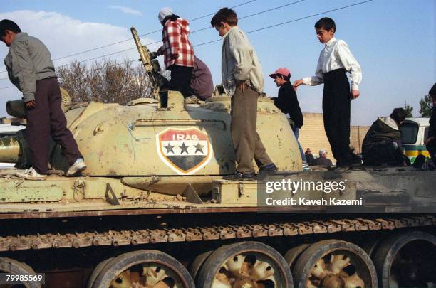 Boys playing on a captured Iraqi tank, which is on display in Behesht-e Zahra cemetery, Tehran, where thousands of those killed in the Iranian...