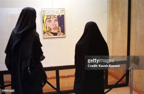 Two female visitors fully covered in Islamic black chador viewing 'The Melody Haunts My Reverie', by American Pop Artist Roy Lichtenstein on display...