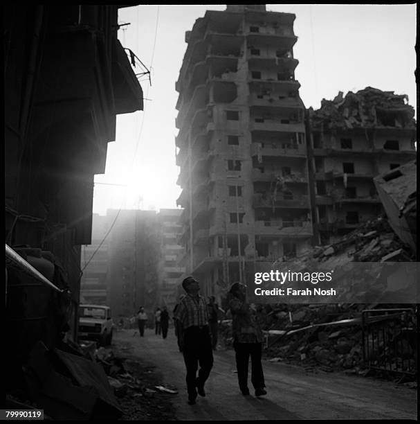 Couple looks up at building destruction as they walk through the rubble on August 31, 2006 in Dahiya, the southern suburb district of Beirut. The...