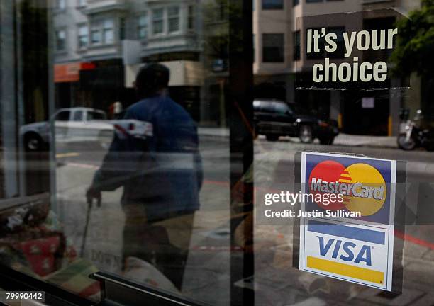 Window sticker advertising Visa and MasterCard credit cards hangs in a window February 25, 2008 in San Francisco, California. Visa Inc. Is hoping...