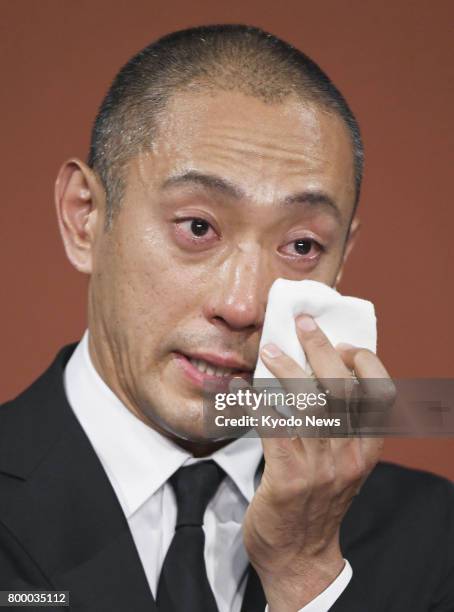 Japanese kabuki star Ichikawa Ebizo wipes away tears during a press conference in Tokyo on June 23 after his wife Mao Kobayashi, a 34-year-old...