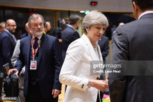British Prime Minister Theresa May talks with other leaders as the UK Ambassador to the EU Tim Barrow looks on, ahead of a roundtabel meeting at the...