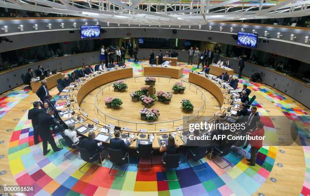 Officials sit in the meeting room at the start of the European Council meeting, on the second day of a summit of European Union leaders and focusing...