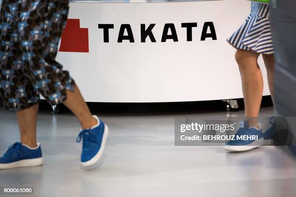 Visitors walk past a logo of the Japanese auto parts maker Takata at a car showroom in Tokyo on June 23, 2017. - Takata shares swung wildly...