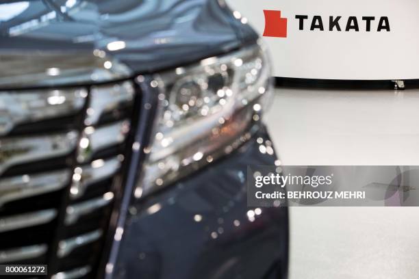 Logo of the Japanese auto parts maker Takata is seen next to a car at a showroom in Tokyo on June 23, 2017. - Takata shares swung wildly rebounding...