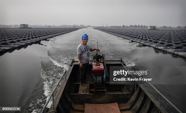 Chinese workers ride in a boat through a large floating solar farm project under construction by the Sungrow Power Supply Company on a lake caused by...