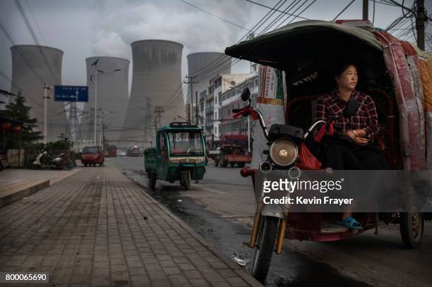 Chinese vendor waits for customers as she sells vegetables at a local market outside a state owned coal fired power plant near the site of a large...