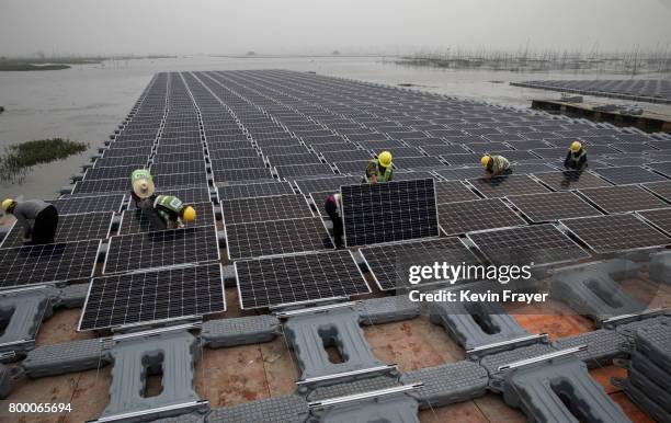Chinese workers prepare panels that are part of a large floating solar farm project under construction by the Sungrow Power Supply Company on a lake...
