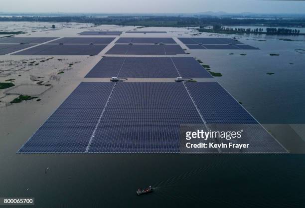 Boat pulls a group of solar panels before being connected to a large floating solar farm project under construction by the Sungrow Power Supply...