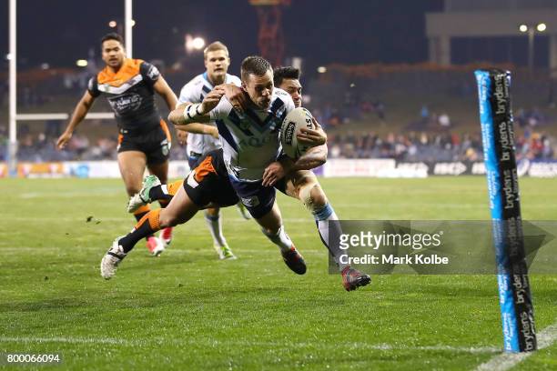 Will Zillman of the Titans scores try as he is tackled by David Nofoaluma of the Tigers during the round 16 NRL match between the Wests Tigers and...