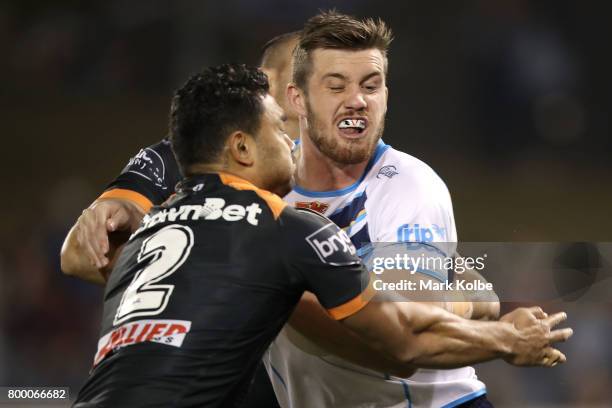 David Nofoaluma of the Tigers tackles Joe Greenwood of the Titans during the round 16 NRL match between the Wests Tigers and the Gold Coast Titans at...